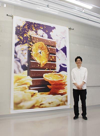 「3m×4mの大型サイズでも15分ほどで出力できます」と小須田マネジャー（出力作品 ©HIRO ISHIKAWA / hue inc.）