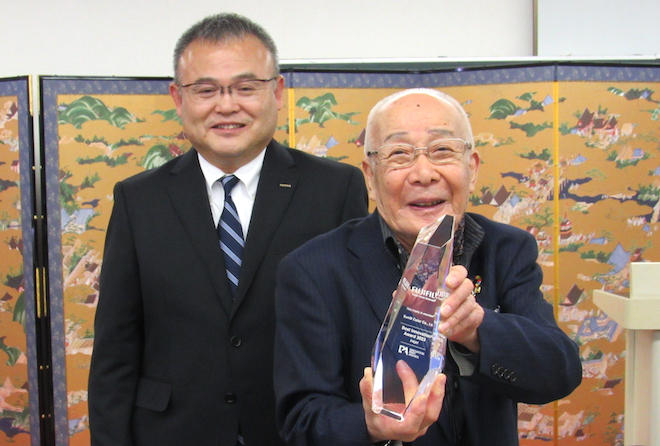 木田執行役員（左）からトロフィーを受け取った松井会長